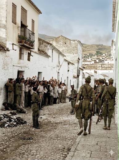 Fotografía de época de una calle durante la Guerra Civil Española, con soldados y población civil.